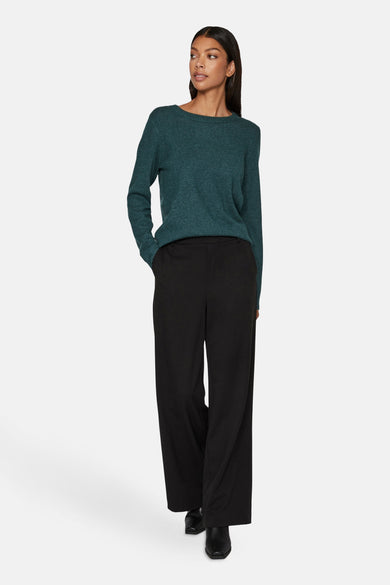 Groene trui met ronde hals van VILA, gedragen met een zwarte, wijde pantalon en zwarte laarsjes.