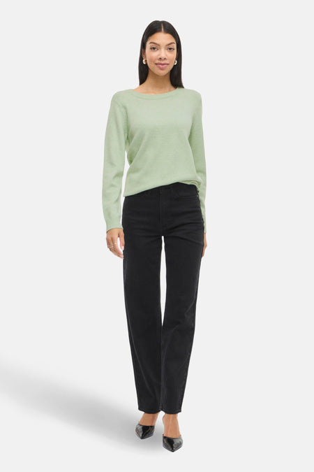 Vrouw met groene trui en zwarte broek.