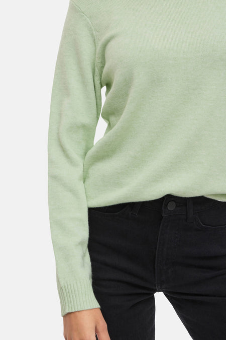 Groene trui en zwarte jeans.