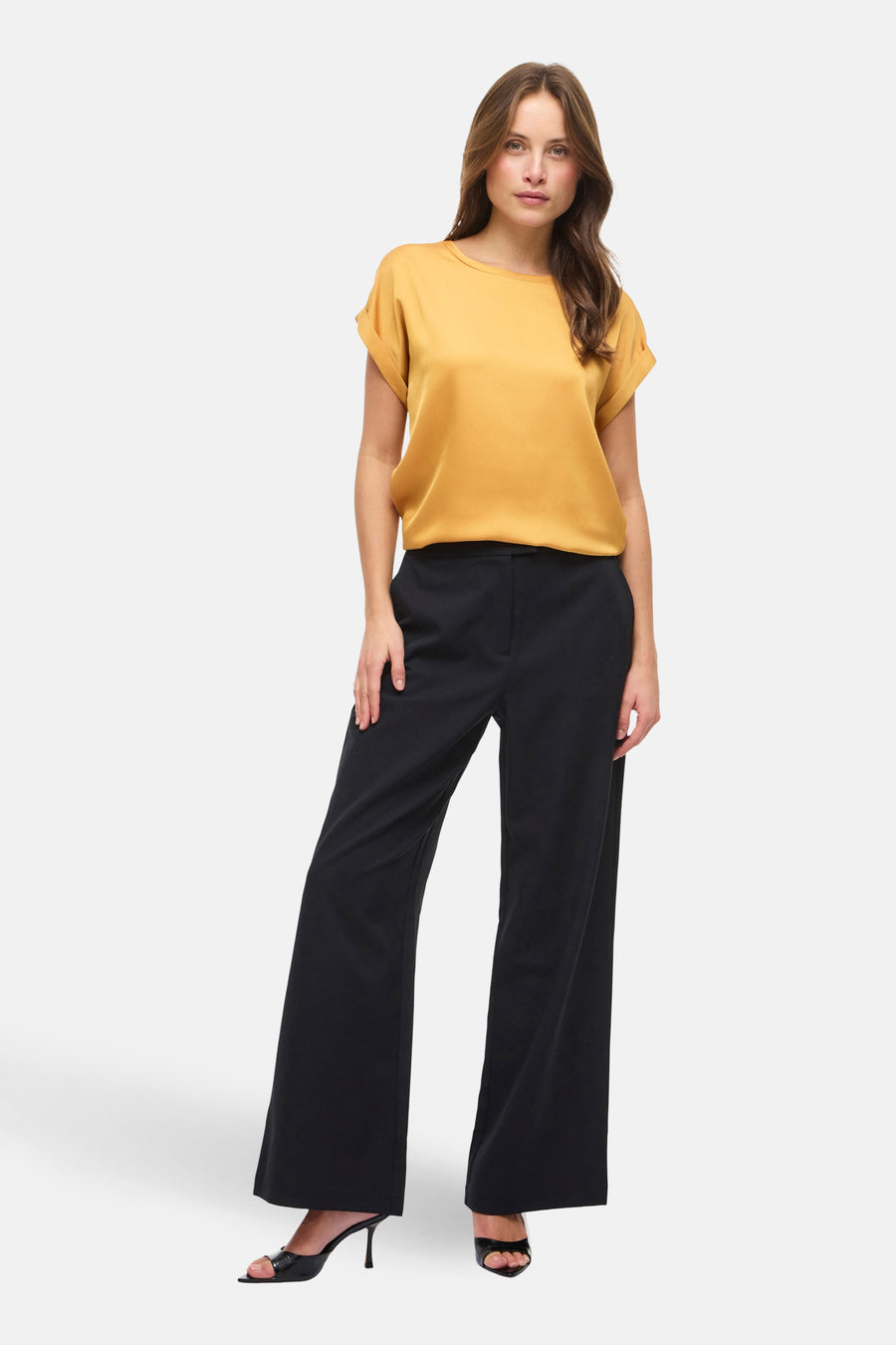 Gouden top met korte mouwen van VILA®, gecombineerd met zwarte, wijd uitlopende broek en zwarte hakken.