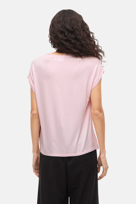 Achterkant van een roze T-shirt op een vrouw met donkere krullen.