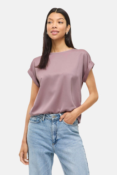 T-shirt rose à manches courtes de VILA®, porté avec un pantalon en cuir et des boucles d'oreilles argentées.