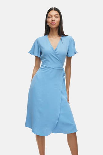 Robe bleue à manches courtes de VILA®, avec un modèle wrap et des sandales rouges.