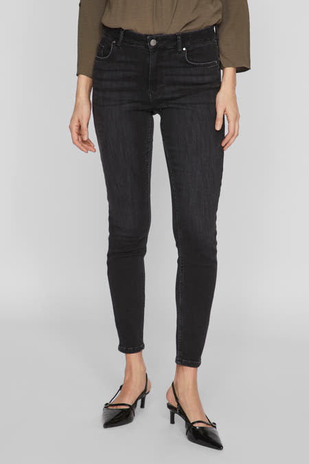 Jean skinny noir de VILA, avec taille haute, porté avec un blouse olive et des talons noirs.