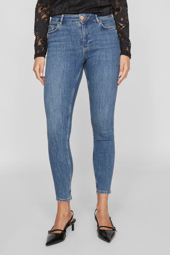 Jean skinny bleu marine de VILA, avec une coupe ajustée et porté avec des talons noirs et un haut en dentelle.