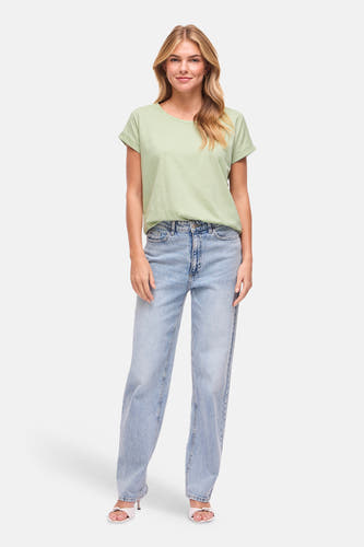 Groen T-shirt met korte mouwen van VILA®, met opgerolde mouwen en gecombineerd met een jeans en witte muiltjes.