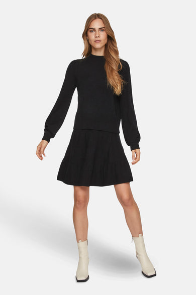 Pull noir avec col montant de Vila, porté avec une jupe noire et des escarpins crème.