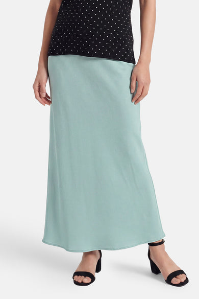 Lange lichtblauwe rok van VILA®, gemaakt van een vloeiende effen stof, gedragen met een zwarte top met stippen en zwarte sandalen.