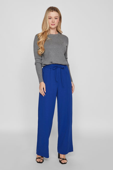 Sweat-shirt gris avec col rond de VILA®, associé à un pantalon bleu et des baskets noires.