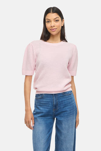 Pull rose de VILA® à manches courtes et à texture tissée, combiné avec un jean ample et des talons noirs.