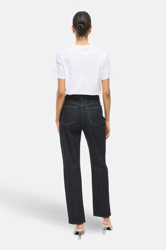 Jean droit bleu marine de VILA, avec des boutons dorés, associé à un T-shirt blanc et à des talons transparents, vu de derrière.