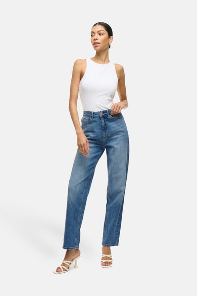VIKELLY mid blue denim straight jeans van VILA, met hoge taille en losse pasvorm, gecombineerd met een witte top en sandalen met hak.
