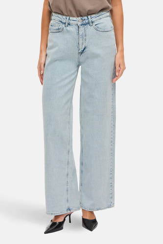 Jean en denim bleu clair large de Vila, avec une jambe droite et porté avec un T-shirt marron.