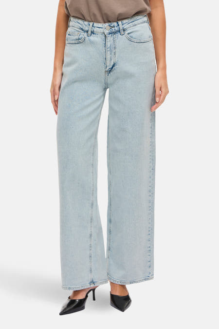 Jean en denim bleu clair large de Vila, avec une jambe droite et porté avec un T-shirt marron.