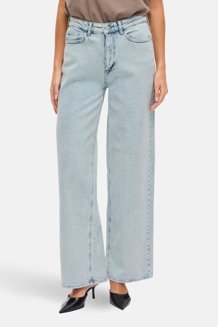 Jean en denim bleu clair large de Vila, avec une jambe droite et porté avec un T-shirt marron.