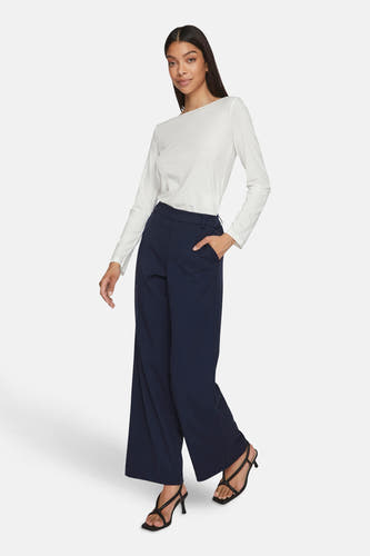 Pantalon bleu de VILA®, associé à une chemise blanche et des baskets noires.