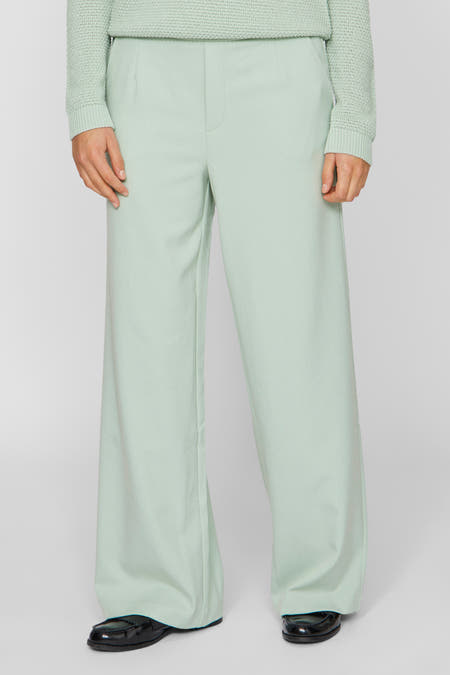 Pantalon vert de VILA, avec des jambes larges et porté avec des chaussures noires.
