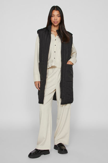 Gilet bodywarmer noir de VILA, avec une coupe longue, doublé et de grandes poches.