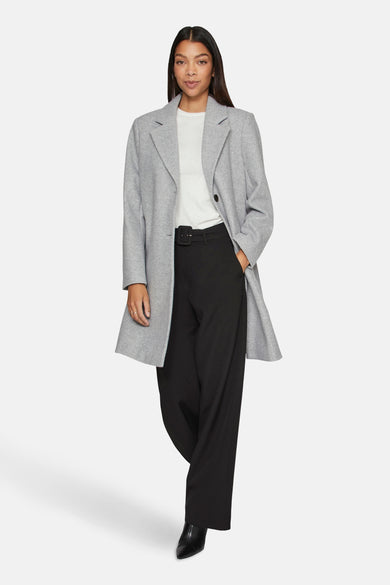 Manteau long gris de VILA, avec une seule boutonnière, porté sur un chemisier blanc et un pantalon noir.