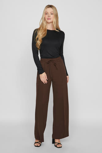Bruine broek van VILA, met wijde pijpen en een strikceintuur, gecombineerd met een zwart shirt en zwarte sandalen.
