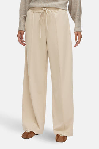 Pantalon beige de VILA, combiné avec un pull de couleur neutre et des chaussures marron.