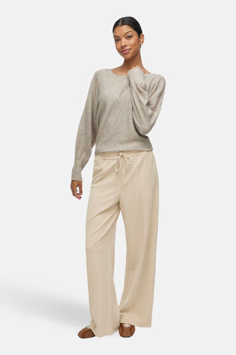 Beige broek van VILA, gecombineerd met een trui in een neutrale kleur en bruine schoenen.