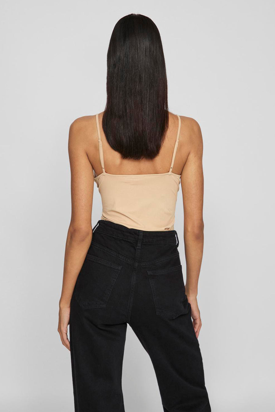 Beige tanktop van VILA, gecombineerd met een zwarte jeansbroek, gezien van achteren.