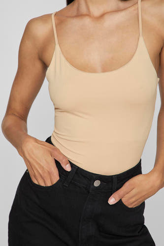 Sous-vêtement beige de VILA, porté avec des jeans noirs les mains dans les poches.
