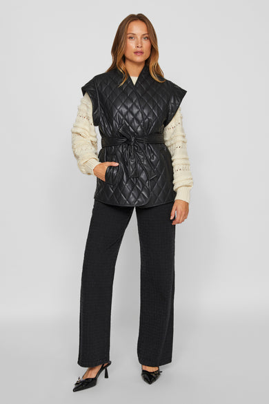 Zwarte bodywarmer van VILA met een gewatteerd ruitpatroon, een strikceintuur en gedragen over een gebreide trui.