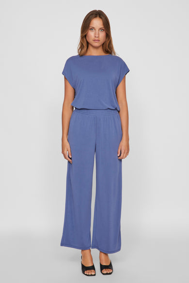 Pantalon bleu de VILA, avec des jambes larges et une ceinture élastique, porté avec des chaussures noires.
