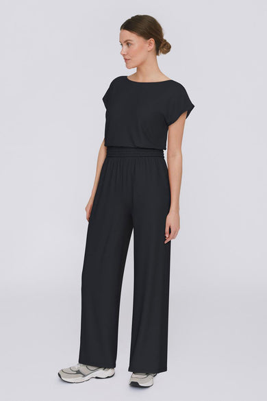 Pantalon noir de VILA, avec des jambes larges et une ceinture élastique, porté avec des baskets.