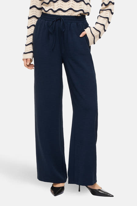 Blauwe colorbroek van VILA, met trekkoord en wijd uitlopende pijpen, gecombineerd met een gestreepte trui.
