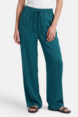 Groene soepelvallende broek van VILA® met wijde pijpen, elastische taille en trekkoord, gedragen met witte top en sandalen.