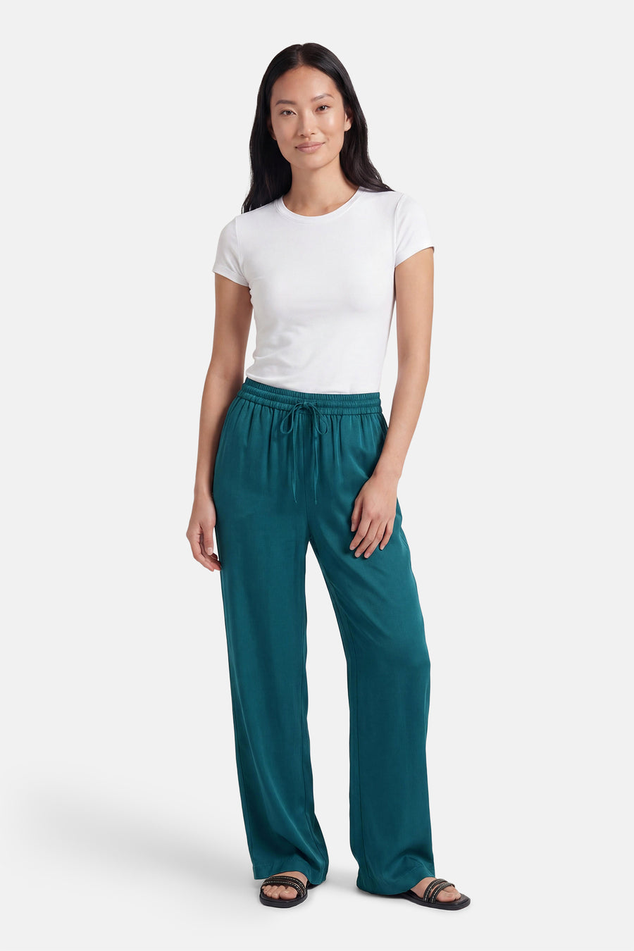 Groene broek van VILA® met wijde pijpen, elastische taille en trekkoord, gedragen met een wit T-shirt en sandalen.