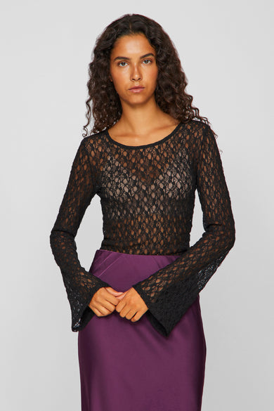Blouse noire à manches longues de VILA®, avec un motif ouvert et des manches larges, associée à une jupe violette.