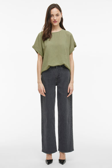 Groen T-shirt met korte mouwen van VILA®, gedragen met donkergrijze jeans en zwarte pumps.
