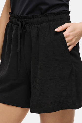 Short noir de VILA avec cordon à la taille et main dans la poche.