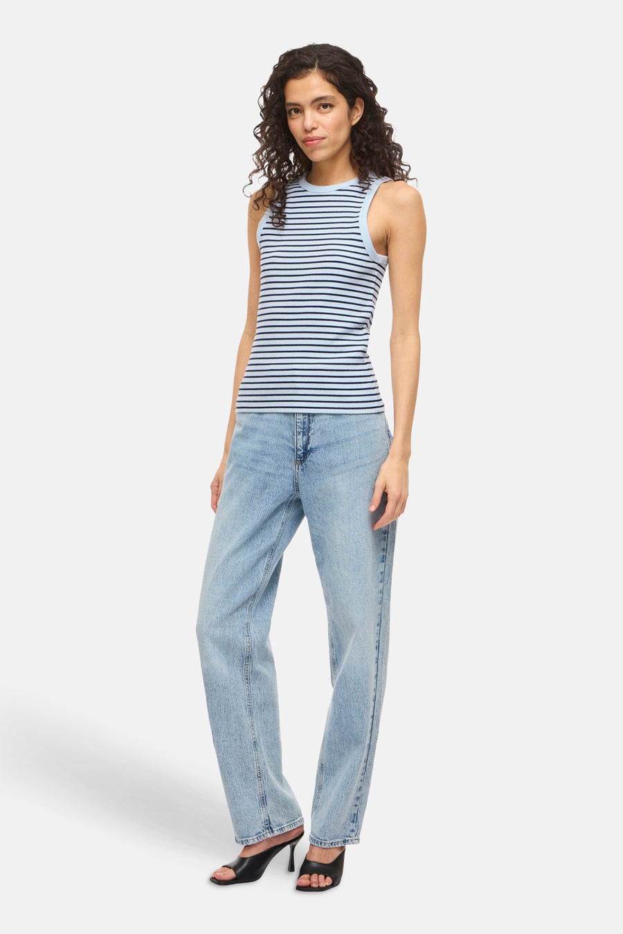 Blauwe top zonder mouwen van VILA®, met een gestreept patroon, gedragen met een blauwe jeans en zwarte hakken.
