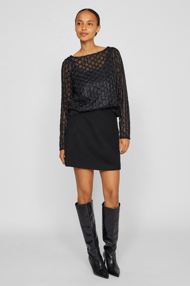 T-shirt noir à manches longues de VILA®, associé à une jupe noire et des bottes noires.