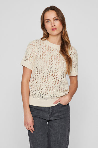 T-shirt écru avec col rond de VILA®, à motif ajouré et porté avec un jean gris.