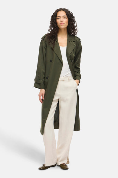 Manteau vert de VILA® porté avec un top blanc et une jupe beige.