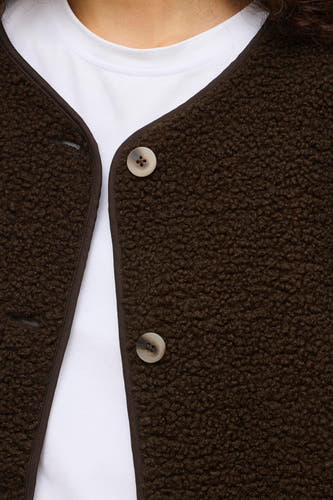 Bruine korte jas van VILA®, met knoopsluiting en een witte T-shirt eronder.