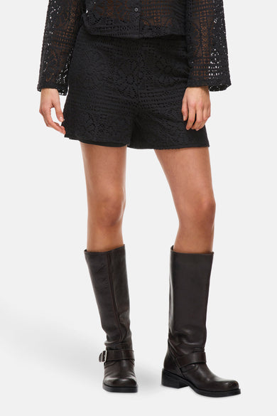 Short noir de VILA avec des détails ouverts, associé à un haut tricoté noir et des bottes en cuir.