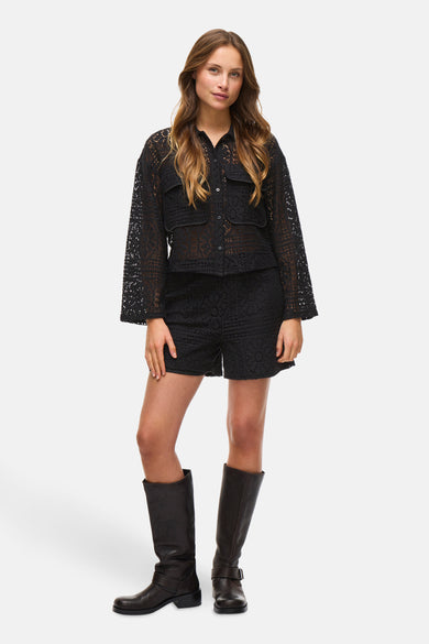 Short noir de VILA, avec un motif de bordure ouverte, combiné à des bottes et une blouse coordonnée.