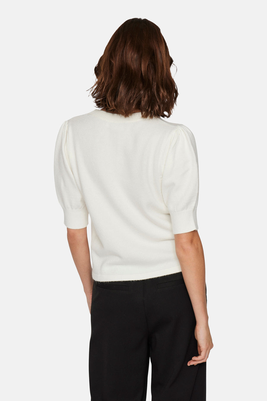 Pull blanc à col rond de VILA, avec des manches courtes bouffantes et associé à un pantalon noir.