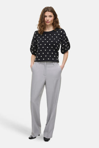 Pantalon gris de VILA®, associé à une chemise noire avec des taches blanches et des baskets noires.