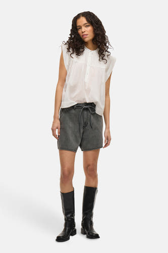 Short gris de VILA avec une ceinture à nouer et porté avec des bottes noires et une blouse blanche.