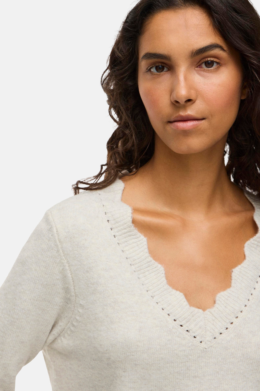 V-hals trui, lichte kleur, gekartelde rand.