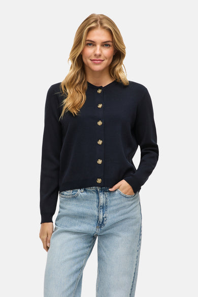 Veste bleue de VILA, avec longues manches et fermeture à boutons, portée avec un pantalon de cuir.