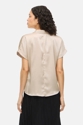 Blouse beige à manches courtes de VILA®, vue de derrière, portée avec une jupe noire plissée.